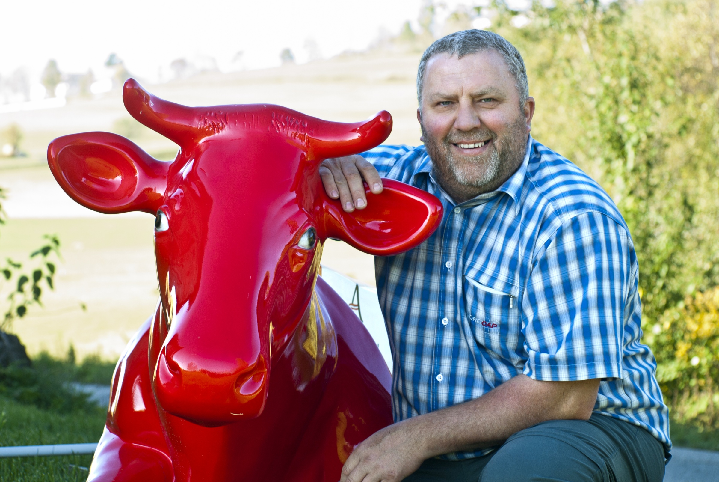 Landwirt Ewald Grünzweil posiert neben eine "A Faire Milch" Kuh.
