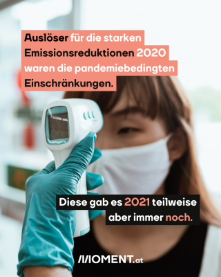 Die Temperatur einer Person wird gemessen. Text: Auslöser für die starken   Emissionsreduktionen 2020   waren die pandemiebedingten   Einschränkungen.  Diese gab es 2021 teilweise   aber immer noch. 