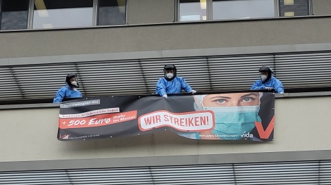 Warnstreik im Ordensspital Göttlicher Heiland in Wien. Beschäftigte hängen Transparent von Balkon.