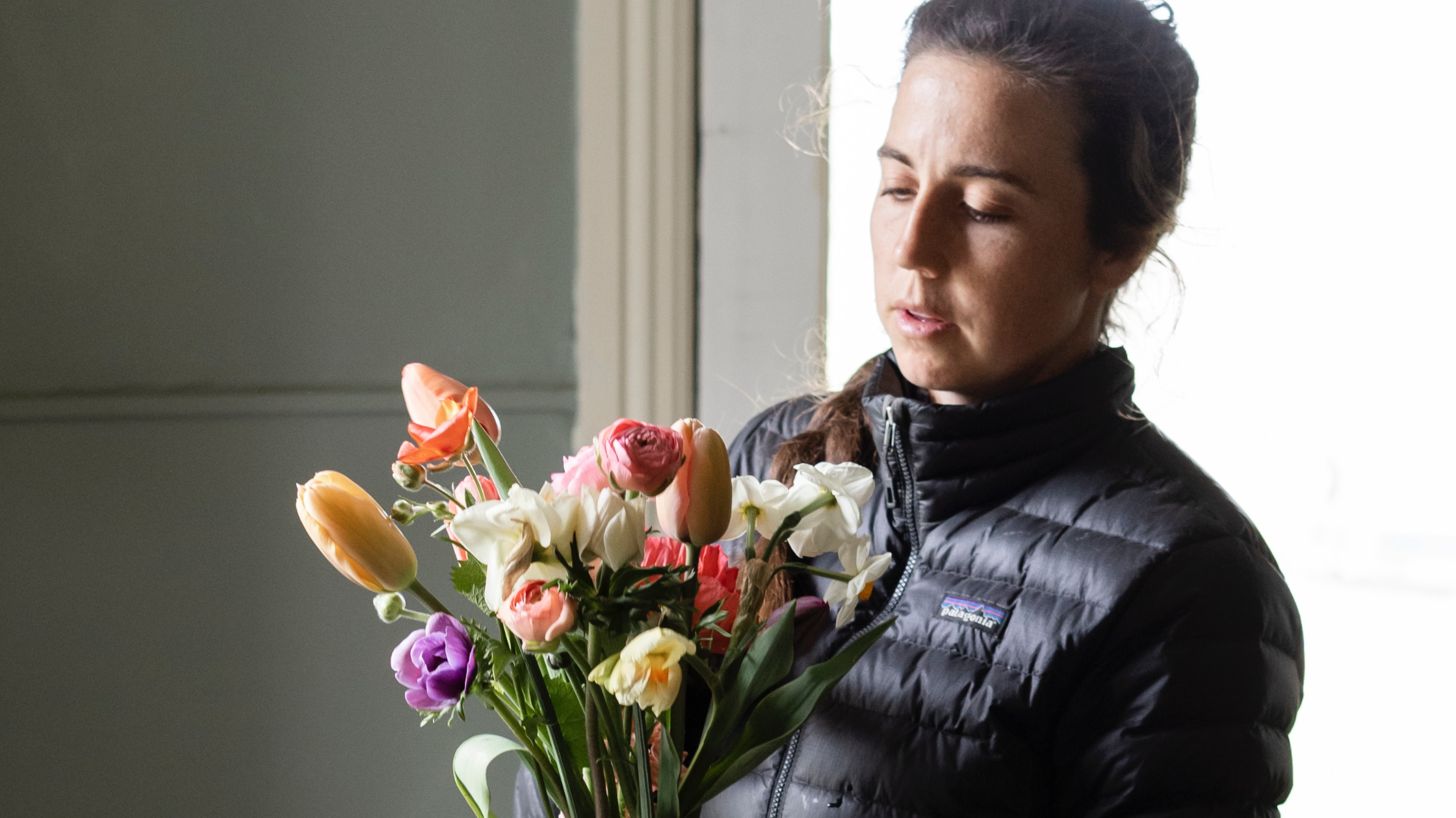 Eine weiblich gelesene Person hält einen Blumenstrauß, an dem sie gerade arbeitet