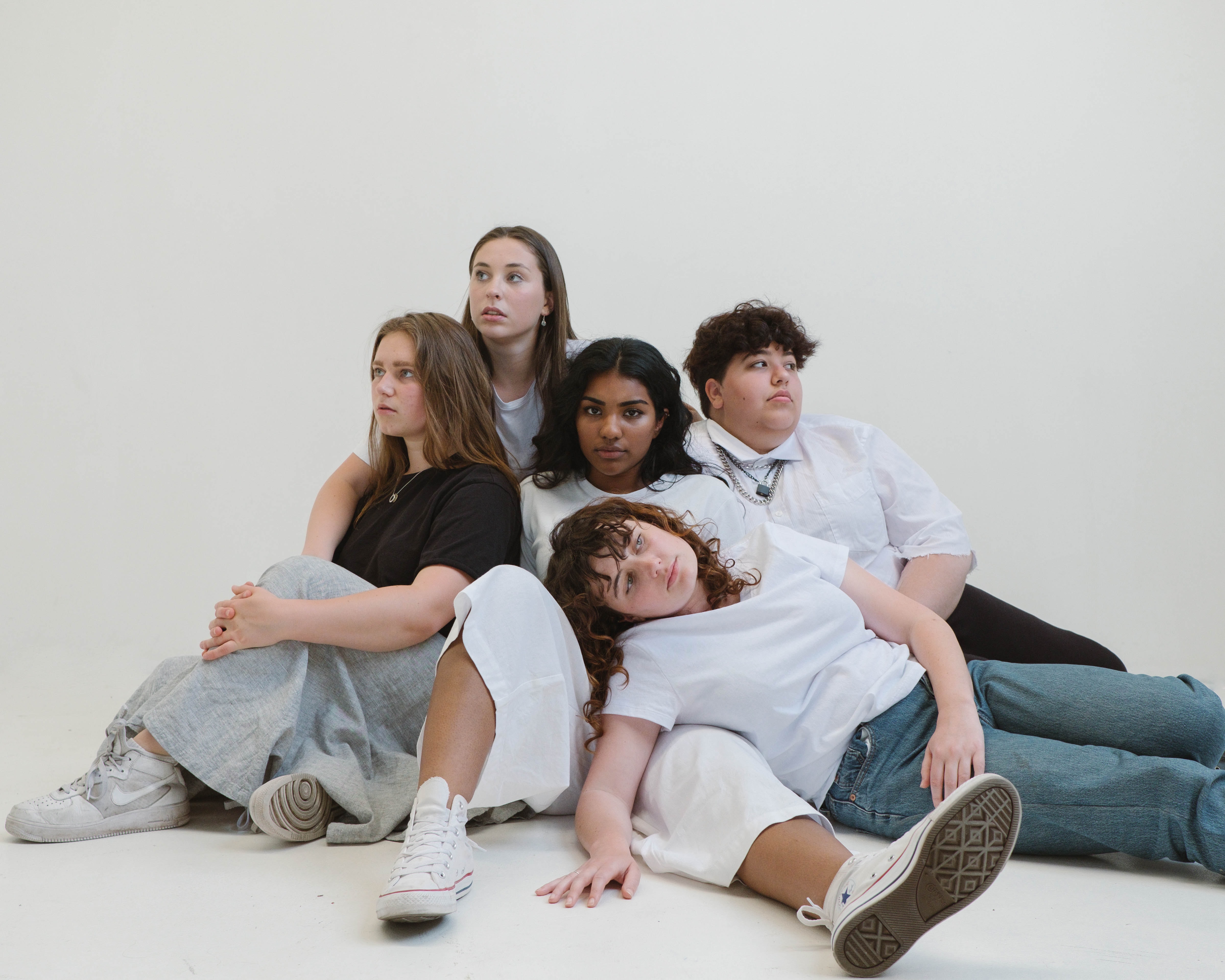 Fünf Personen sitzen dicht beieinander vor weißen Hintergrund