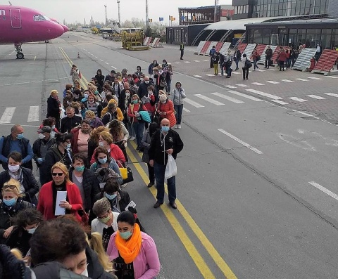 HeimbetreuerInnen warten darauf das Flughafen in Timisoara boarden zu dürfen. Die Gruppe steht mit Mund-Nasen-Schutz auf dem Rollfeld des Fughafens.