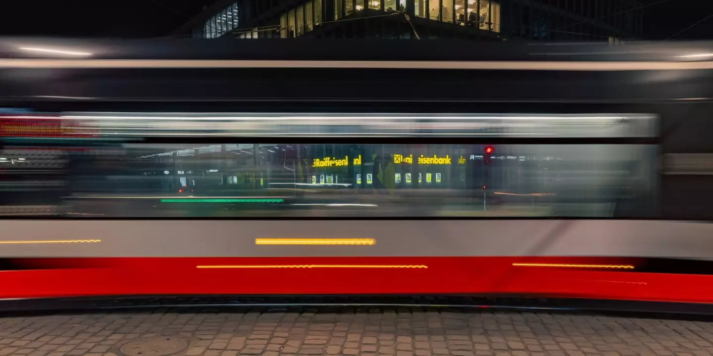 Straßenbahn vor Raiffeisen-Filiale. Österreichs Banken reichen Gewinne aus Zinsen nicht an Kund:innen weiter.