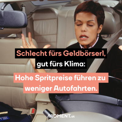 Eine Frau mit schwarzem Oberteil und kurzen, schwarzen Haaren sitzt auf dem Fahrersitz eines Autos. Sie ist angeschnallt. Sie hat die Hände in Frustration vom Lenkrad gehoben. "Schlecht fürs Geldbörserl, gut fürs Klima: Hohe Spritpreise führen zu weniger Autofahrten."