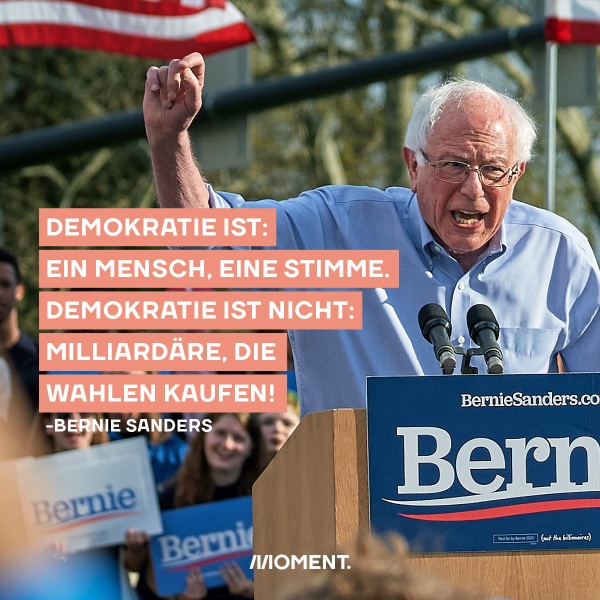 Bernie Sanders hält eine Rede und sagt mit erhobenem Arm: Demokratie ist: Ein Mensch, eine Stimme. Demokratie ist nicht: Milliardäre, die Wahlen kaufen.