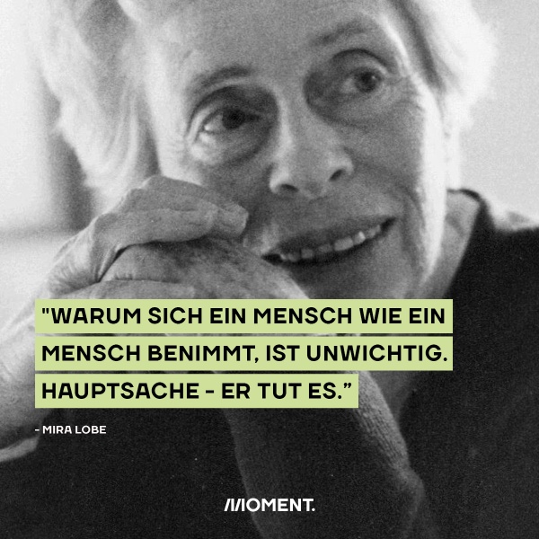 Mira Lobe hat die Arme auf dem Tisch abgestützt und grinst in die Kamera: "Warum sich ein Mensch wie ein Mensch benimmt, ist unwichtig. Hauptsache er tut es."