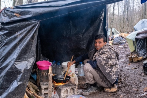 Ein Geflüchteter kocht eine Mahlzeit im gatschigen Not-Waldcamp in Velika Kladuša. 