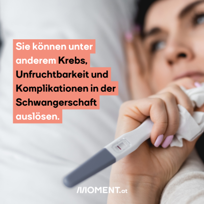 Eine Frau liegt im Bett. Man sieht nur verschwommen ihren Kopf. Im Vordergrund sieht man,dass sie einen Schwangerschaftstest in der Hand hält.