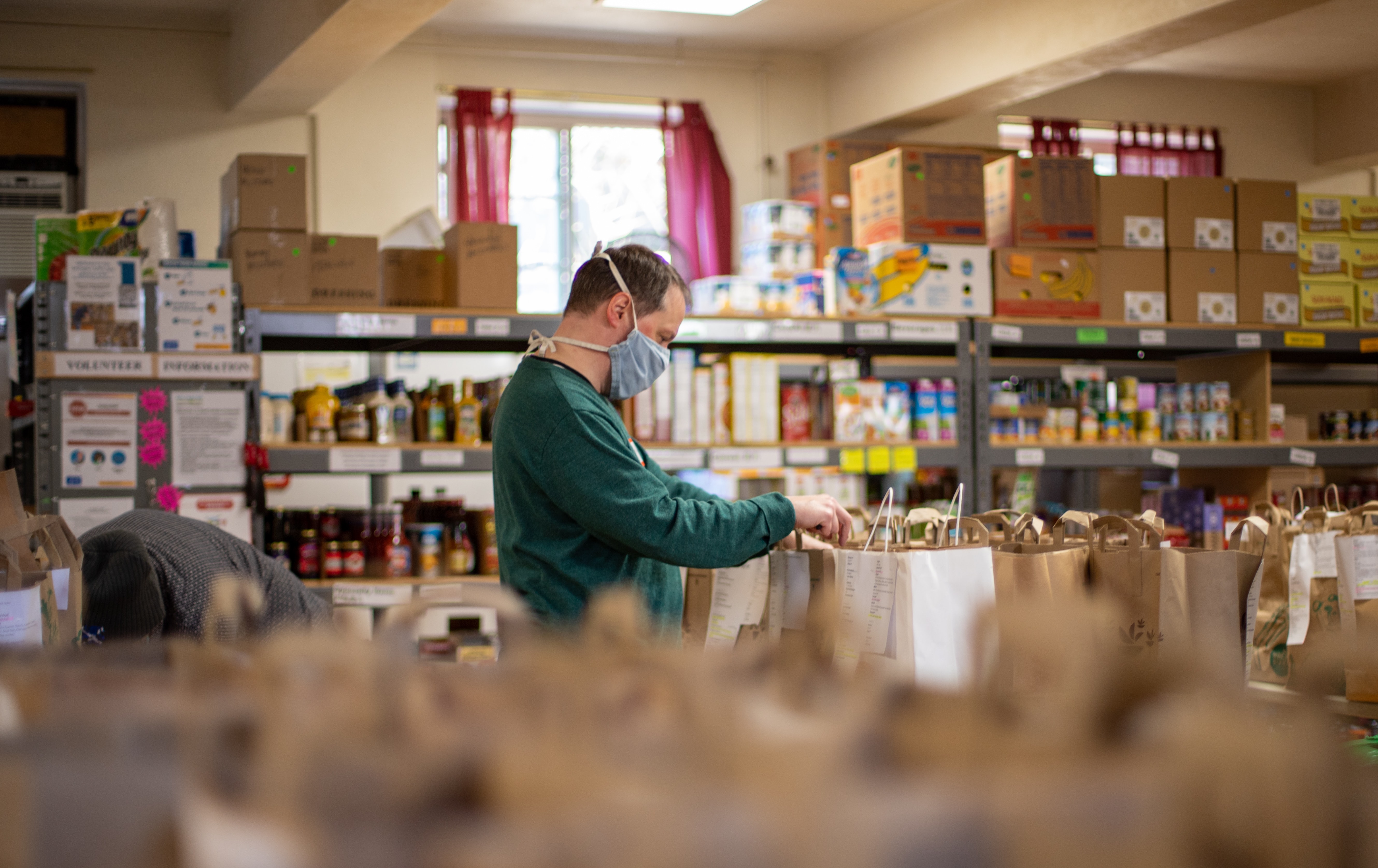 (Gemeinnützige) Arbeit statt Haft: Zu sehen ist ein Mann in einem Markt, der Sackerl mit Lebensmitteln zusammenstellt.