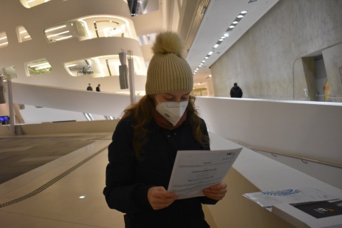 Studieren als Arbeiterkind: Anna steht mit Mütze und Haube im Hauptgebäude der WU und hält ihr Abschlusszeugnis in der Hand