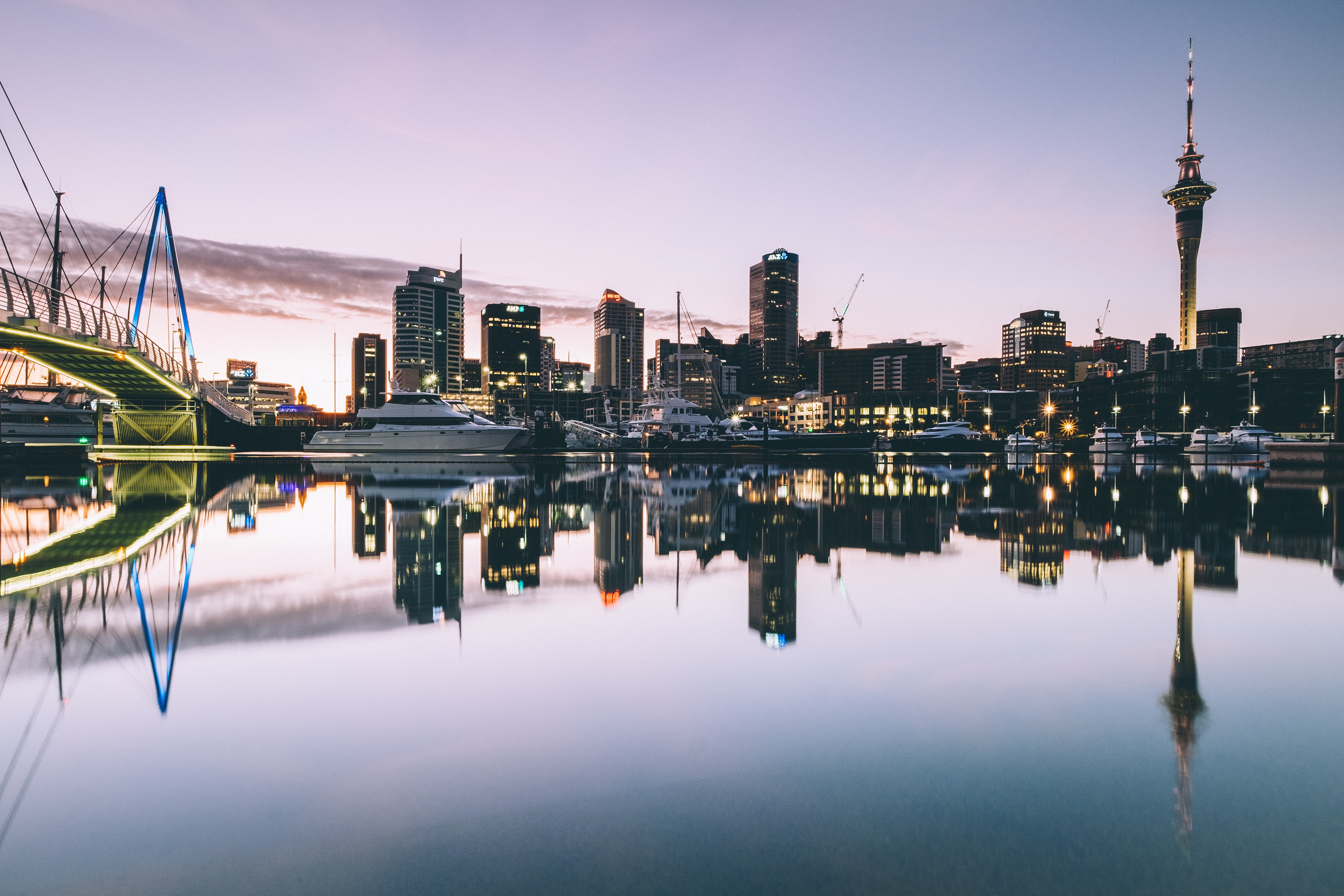 Wählen ohne Staatsbürgerschaft: Zu sehen ist die Skyline von Auckland, Neuseeland. Zahlreiche Schiffe liegen im ruhigen Wasser, die Hochhäuser spiegeln sich auf der Wasseroberfläche.