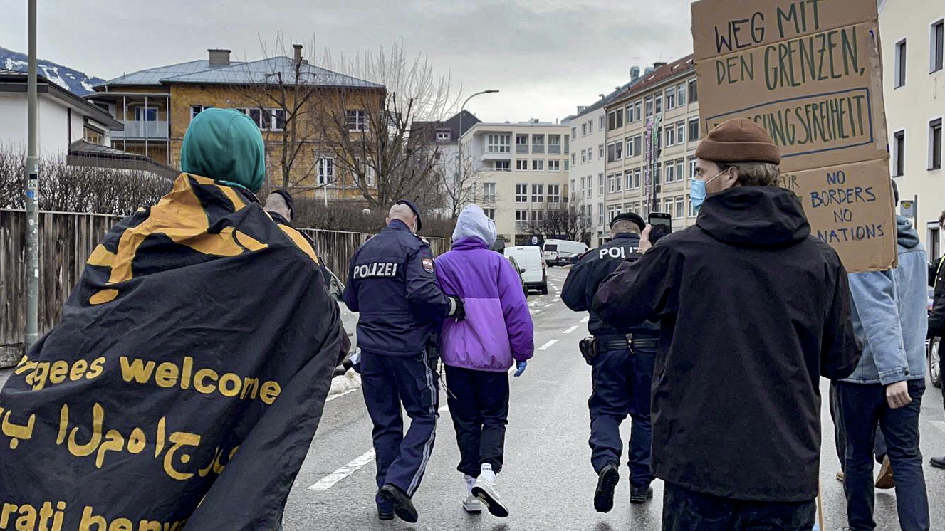 Auf dem Foto zu sehen ist ein Polizist, der eine Person in lila Jacke abführt. All das findet auf einer Demo statt. Im Artikel geht es um Rassimus von der Polizei.