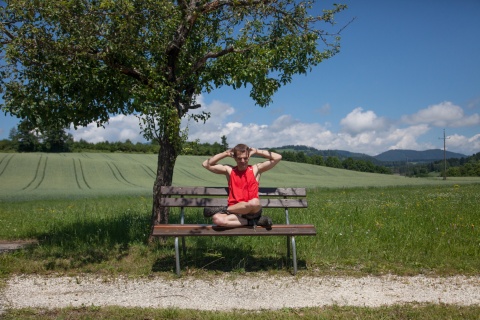 Das Bild der Diakonie zeigt einen Sportler mit Autismus im Grünen, der auf einer Bank Dehnübungen macht.