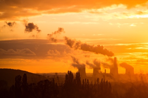 Kohlekraftwerk Ratcliffe-on-Soar, England. Zu sehen sind vier Meiler eines Kohlekraftwerks, die Rauch ausstoßen und in rötliches Sonnenlicht getaucht sind.