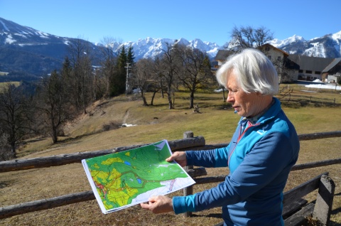 Eine Frau mit Bauplänen in der Hand vor Natur