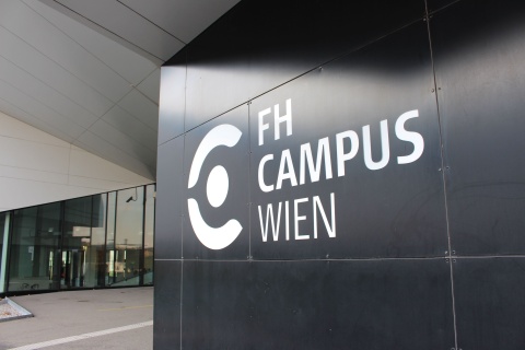 Zu sehen ist das Gebäude der FH Wien Campus. Ein schwarzes Gebäude mit Logo. Im Artikel geht es um Hebammenmangel in Österreich.