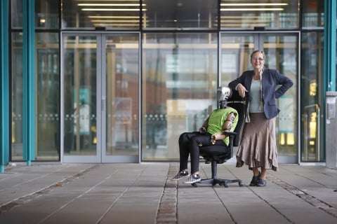 Astrid Linder mit EvaRID Prototyp, der in einem Bürosessel sitzt.