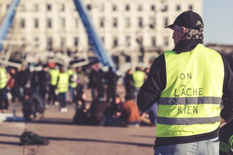Protest der Gelbwesten - zu sehen ist ein Mann mit gelber Warnweste, auf dem Rücken trägt er die Aufschrift "On Lâche Rien".