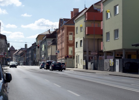 Foto von der Grazer Straße in Wiener Neustadt, die durch die Ostumfahrung entlastet werden soll. Auf dem Foto zu sehen ist die Straße, ein paar Autos vor einer roten Ampel und Häuser.