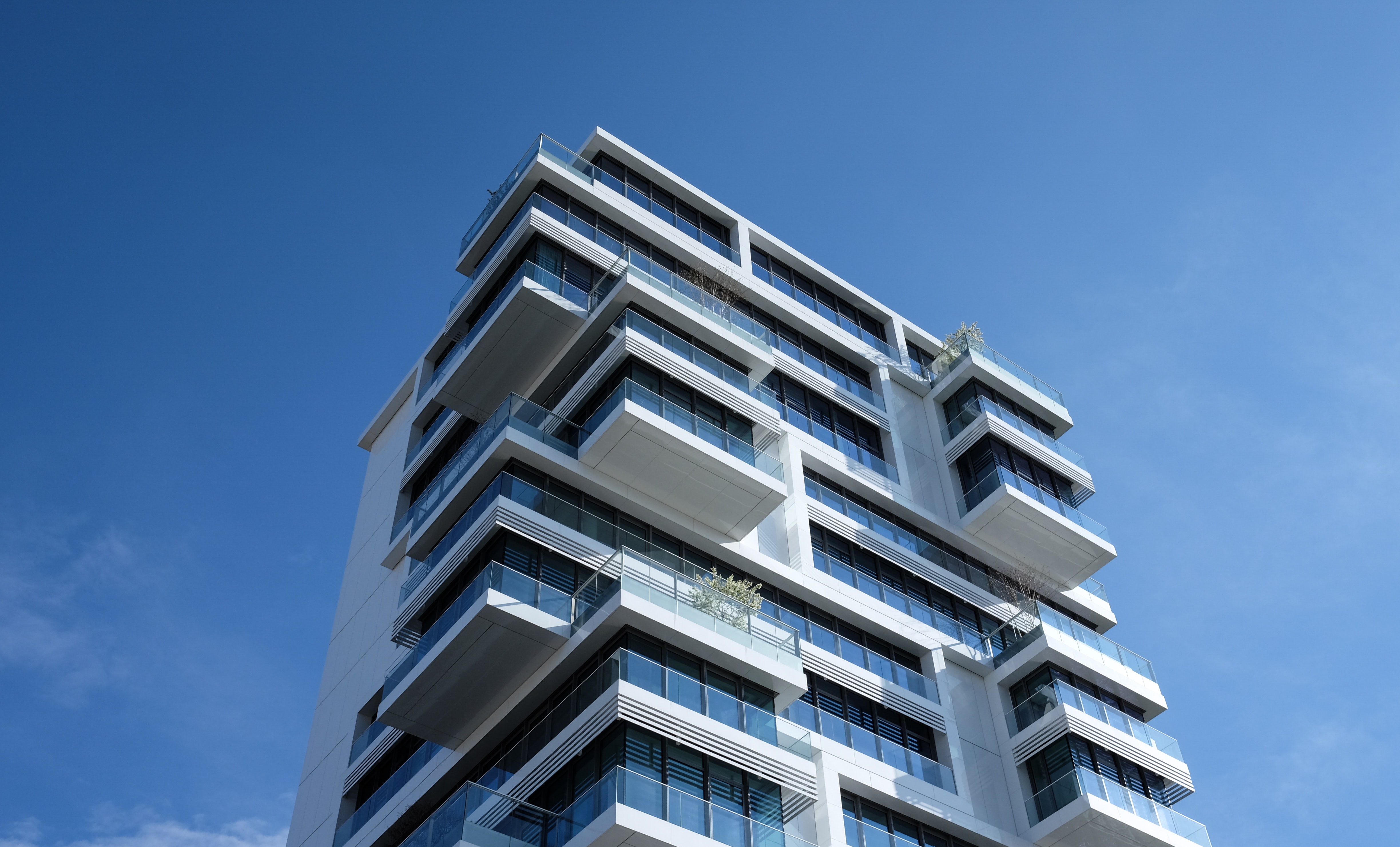 Ein neues Wohngebäude mit zahlreichen Balkonen ragt in den blauen Himmel. Im Beitrag geht es um Ablösen bei Genossenschaftswohnungen.
