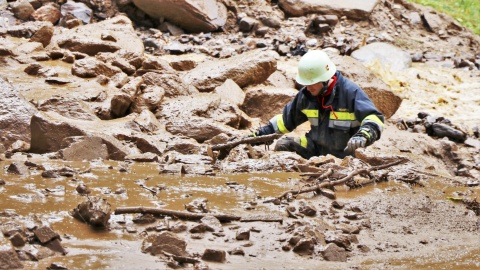 Feuerwehrmann in Feld am See watet durch hüfthohen Schlamm.