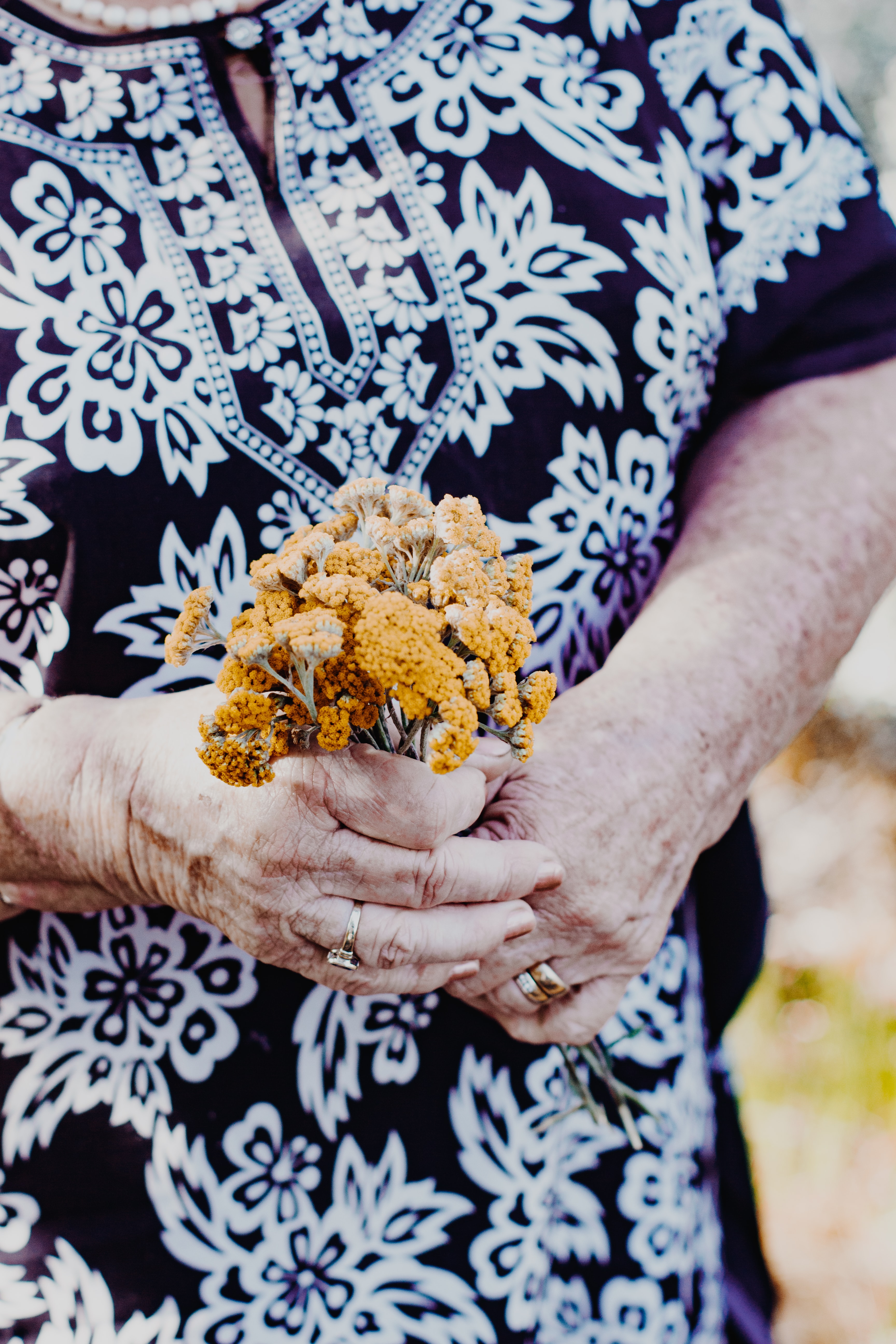 Eine Mindestpensionistin hält Wiesenblumen in der Hand.