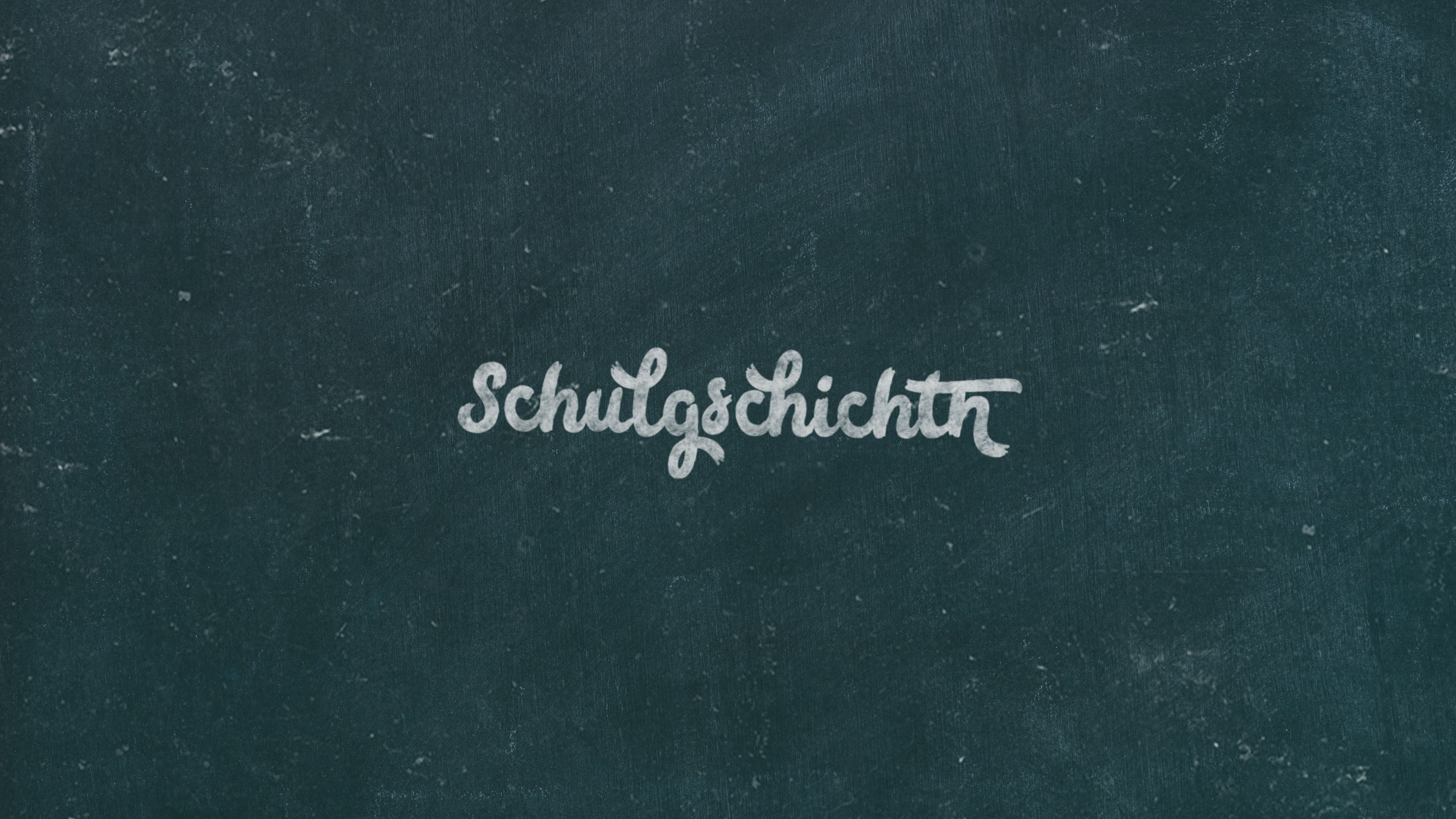 Eine Tafel, auf der mit Kreide das Wort "Schulgschichtn" geschrieben wurde.