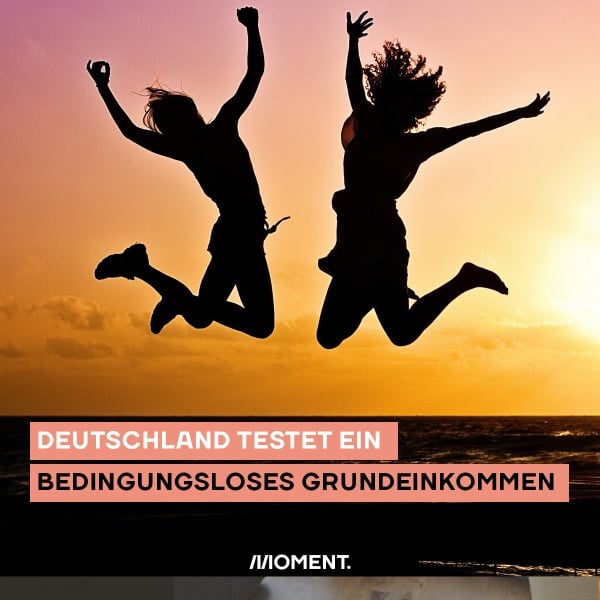 Zwei Menschen springen am Strand in die Luft. Sie strecken die Arme freudig von sich und sind im Sonnenuntergang nur als schwarze Kontraste erkennbar. Text: Bedingungsloses Grundeinkommen: Deutschland startet Pilotprojekt.