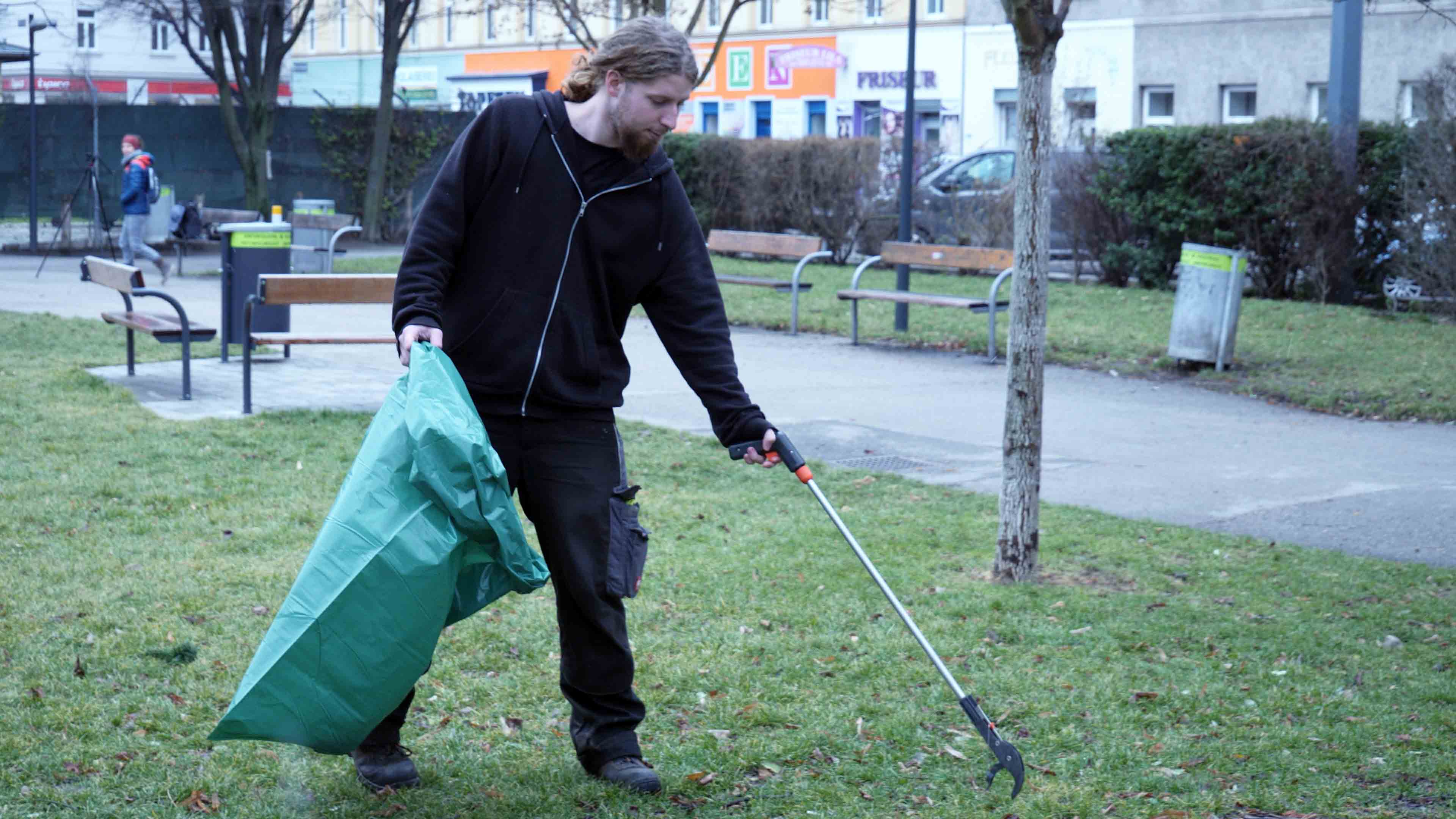 Niko sammelt Müll in einem Park ein