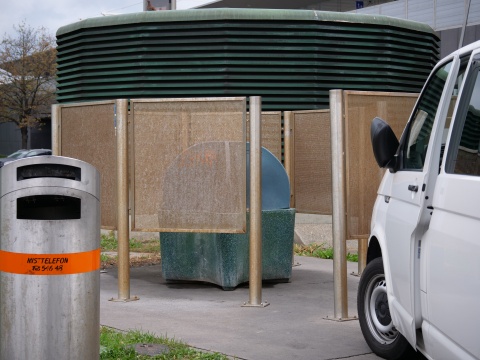 Ein Urinal auf der Straße, das mit Trennwänden aus Plastik Privatsphäre schaffen, davor ein Sichtschutz.