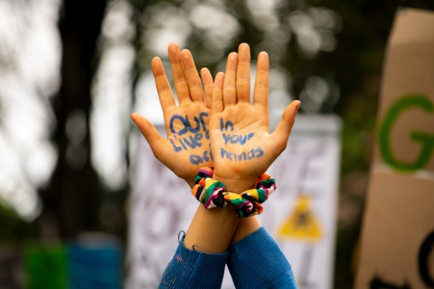 Nahaufnahme von zwei Handflächen auf denen der Schriftzug "Unser Leben ist in euren Händen" zu lesen ist. (Foto: Paddy O'Sullivan/Unsplash)