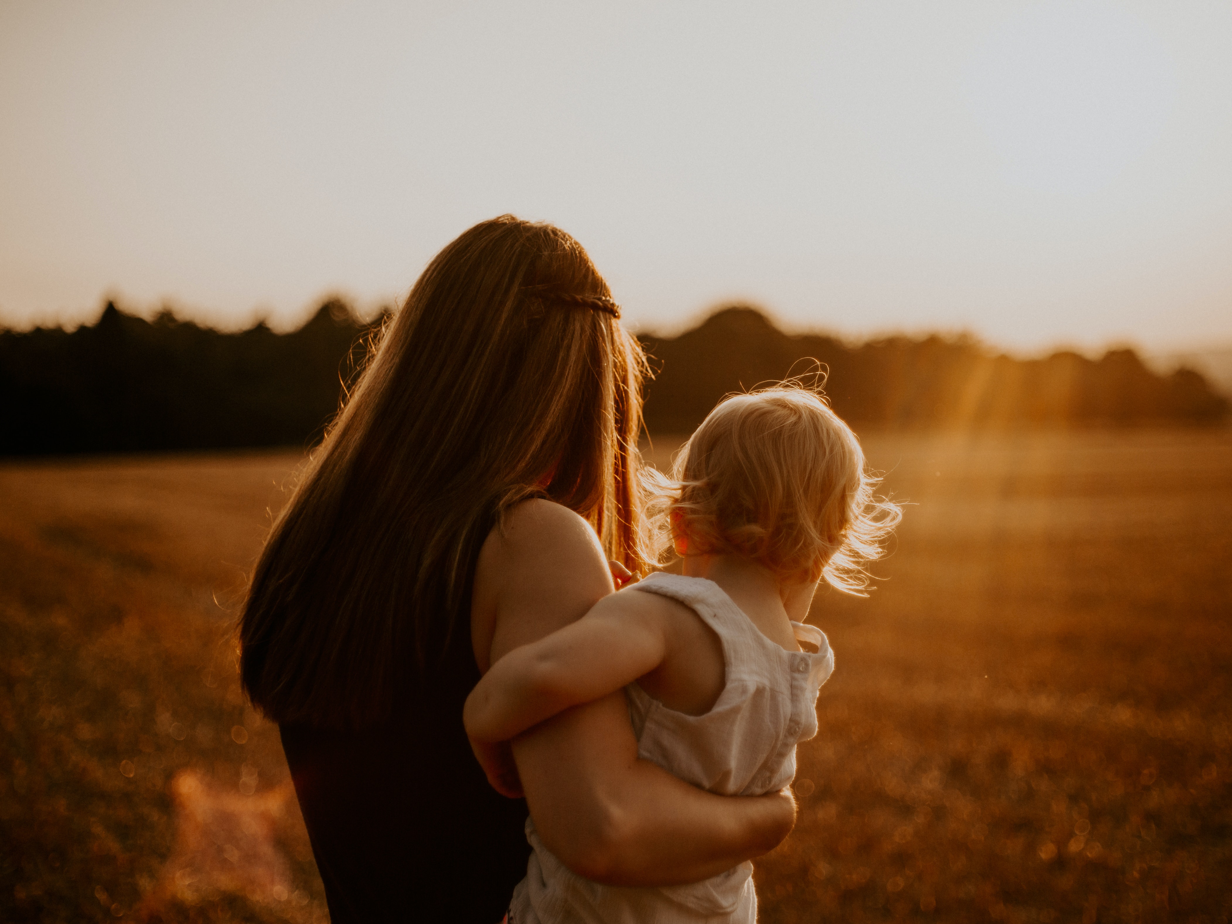 Eine Mutter mit ihrem Kleinkind blickt in den Sonnenuntergang