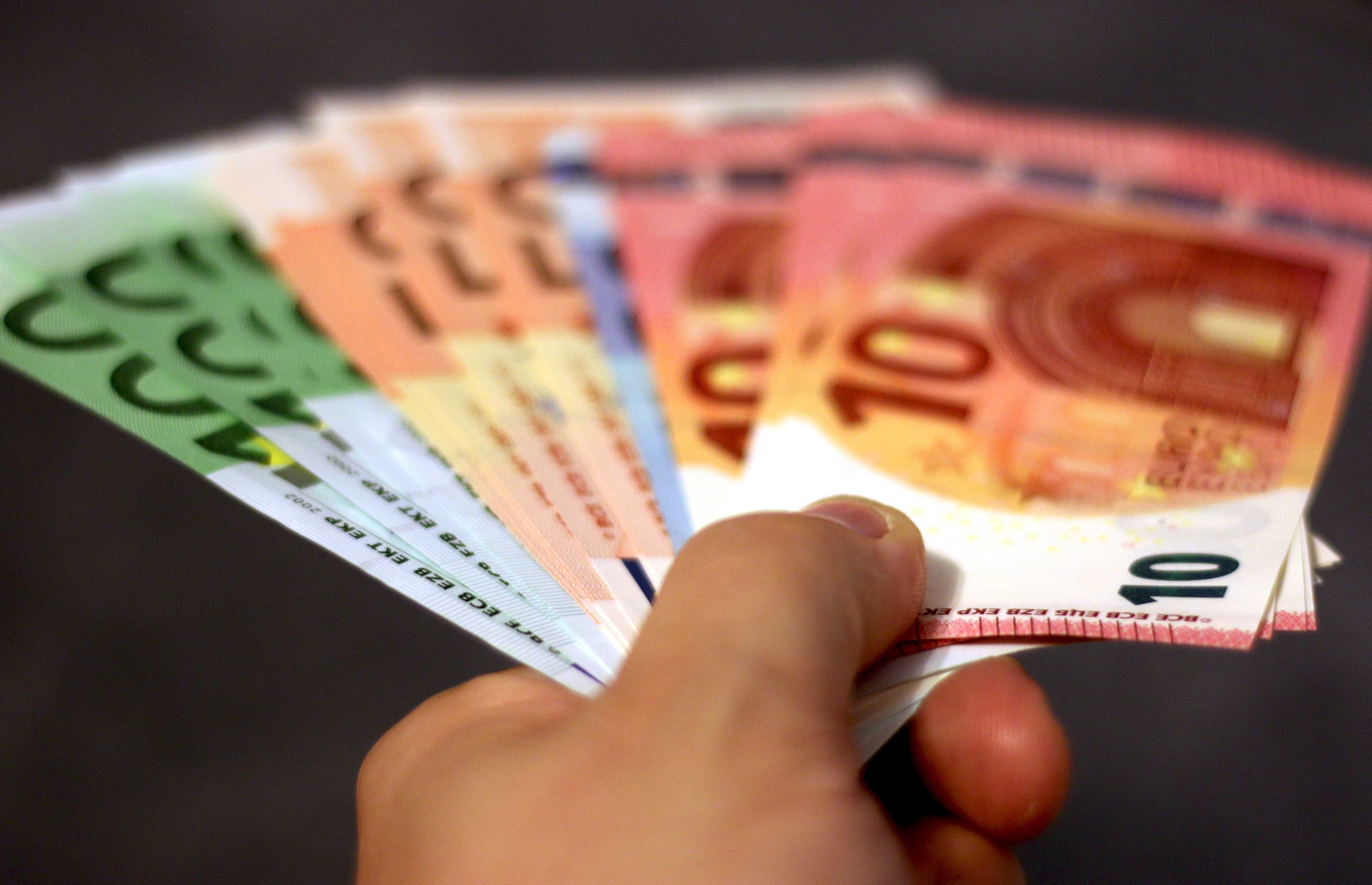 Eine Hand hält verschiedene Euro-Scheine gefächert. Bebildert wird ein Artikel zu Einmalzahlungen statt Lohnerhöhungen.