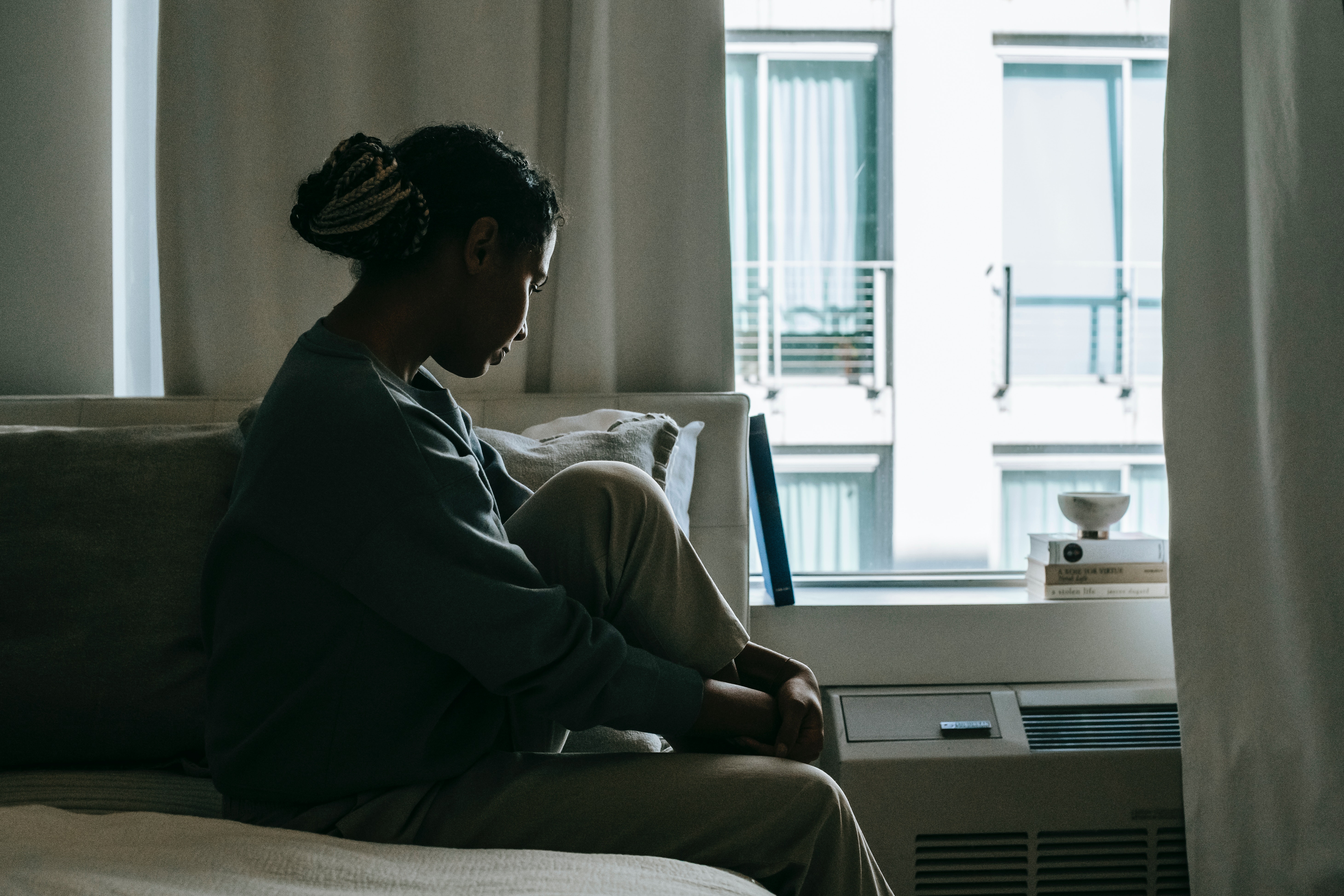 Frau sitzt an einem Fenster in der Psychatrie.