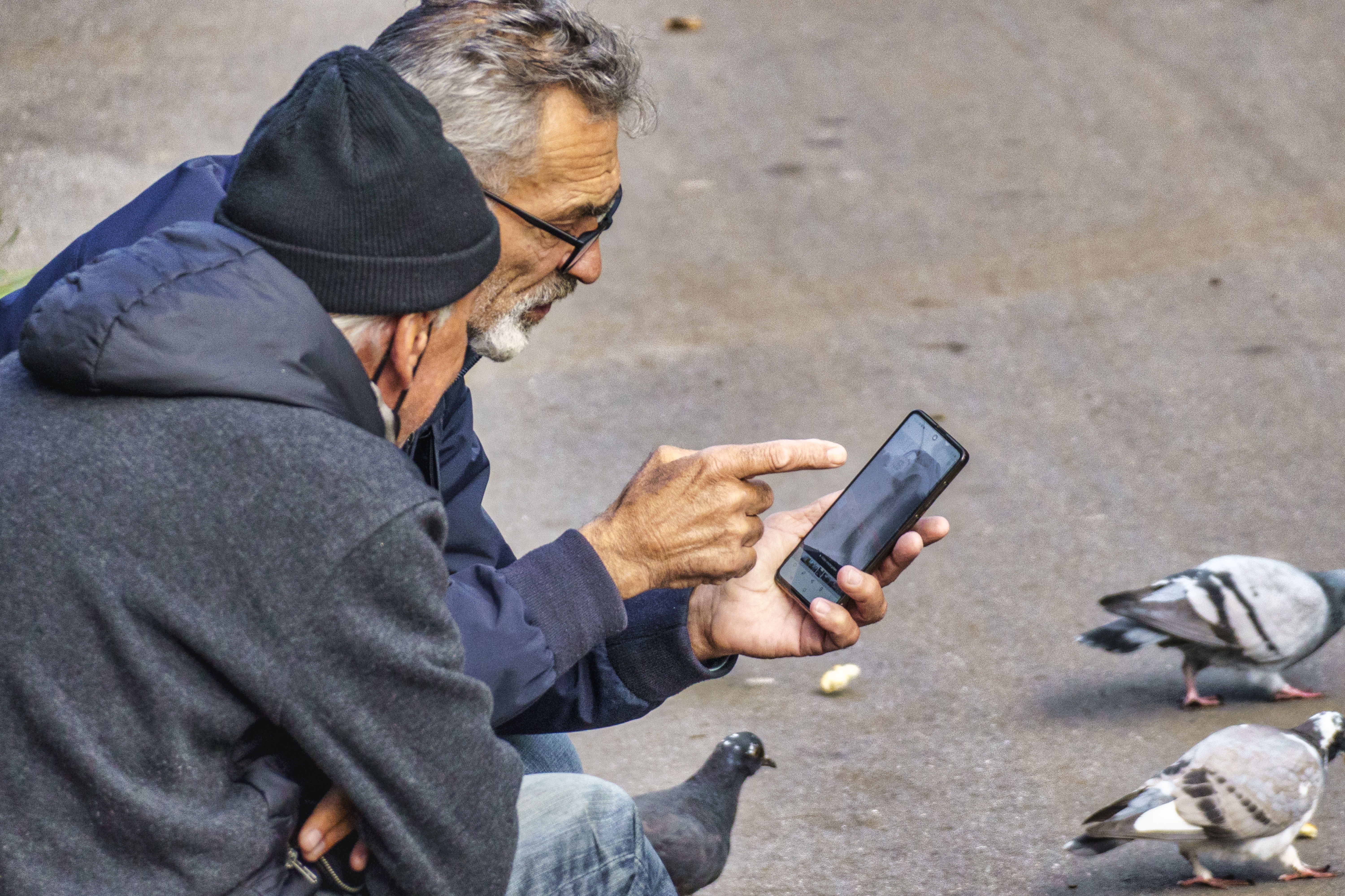 Registrierung für ID Austria: Zwei ältere Männer schauen in ein Handy.