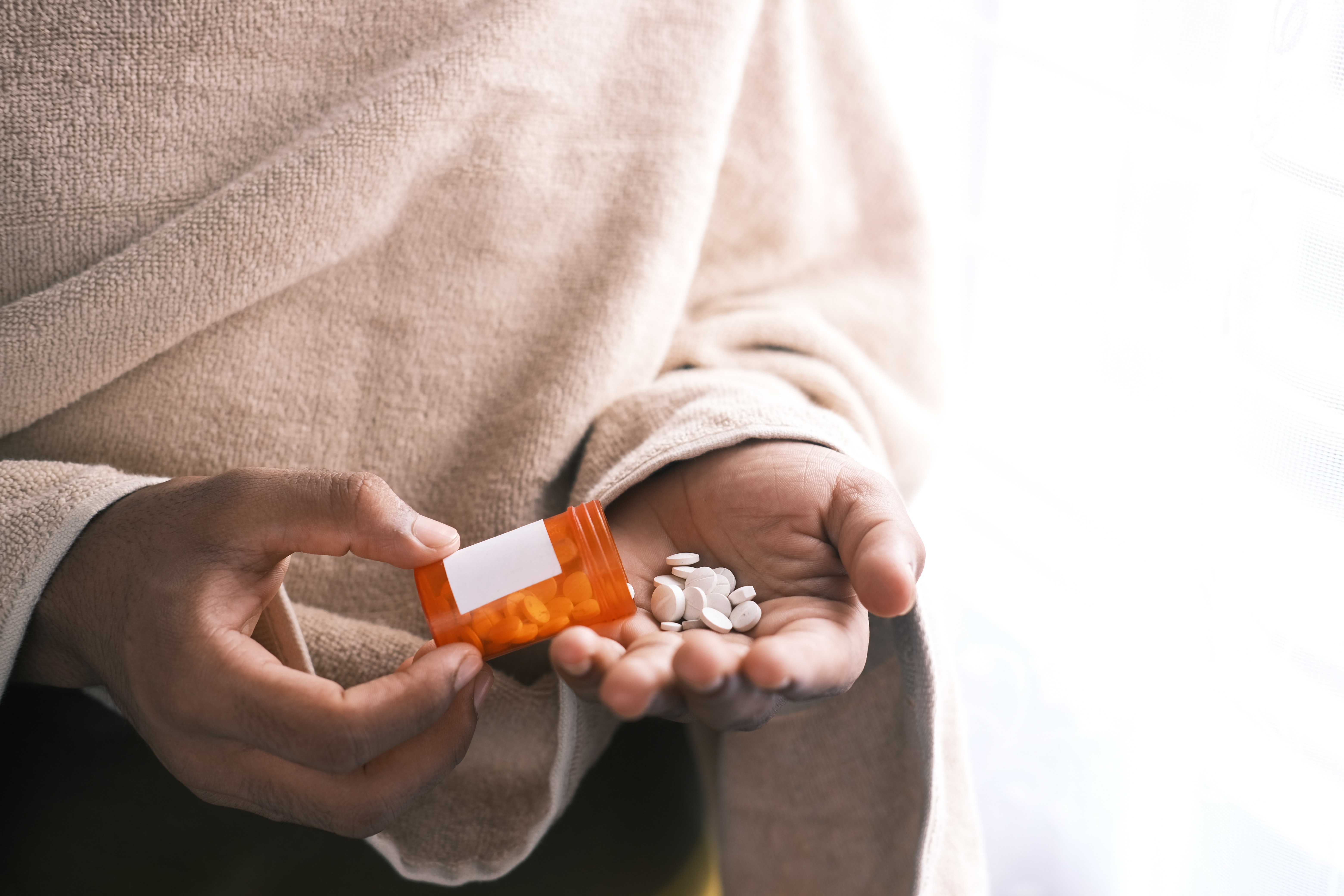 Ein Mann hält Tabletten in seiner Hand.