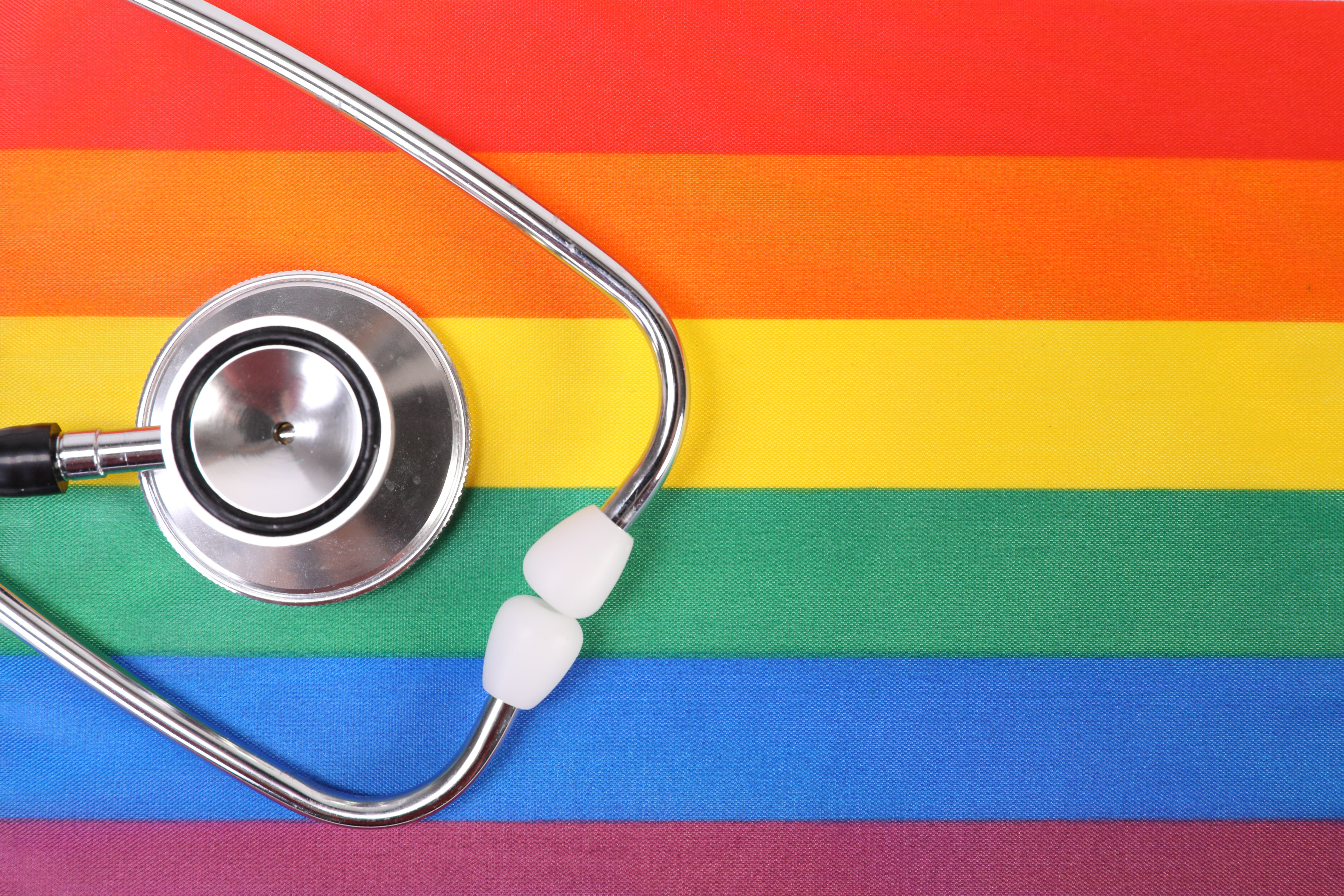 Stethoskop vor einer Regenbogenflagge als Symbol für Diskriminierung in der Medizin der LGBTQIA+ Community.