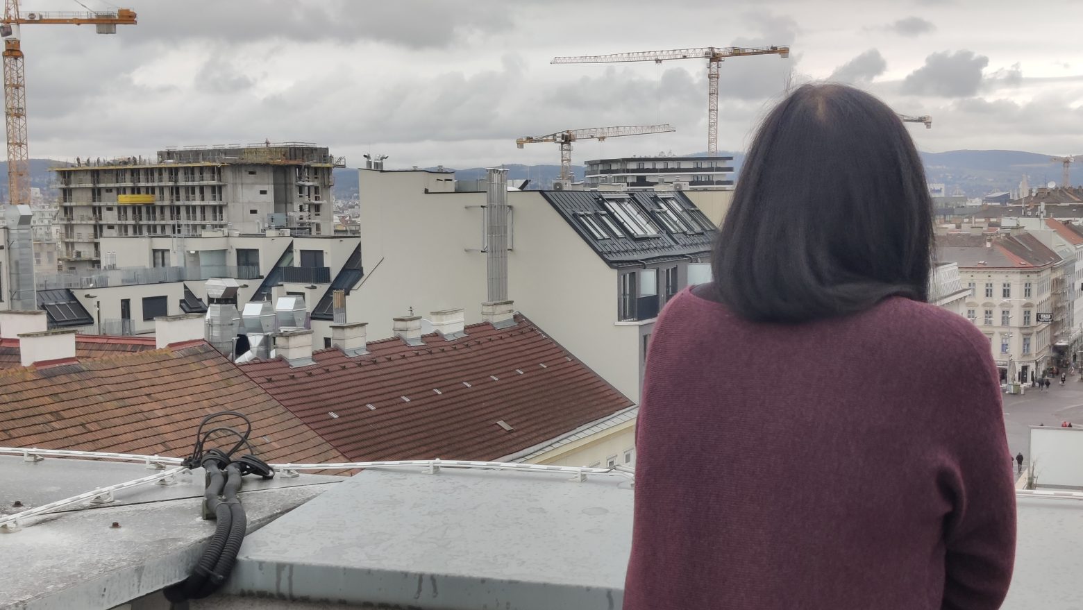 Care-Leaverin Melanie schaut vom Balkon auf anonyme Dächer in Wien