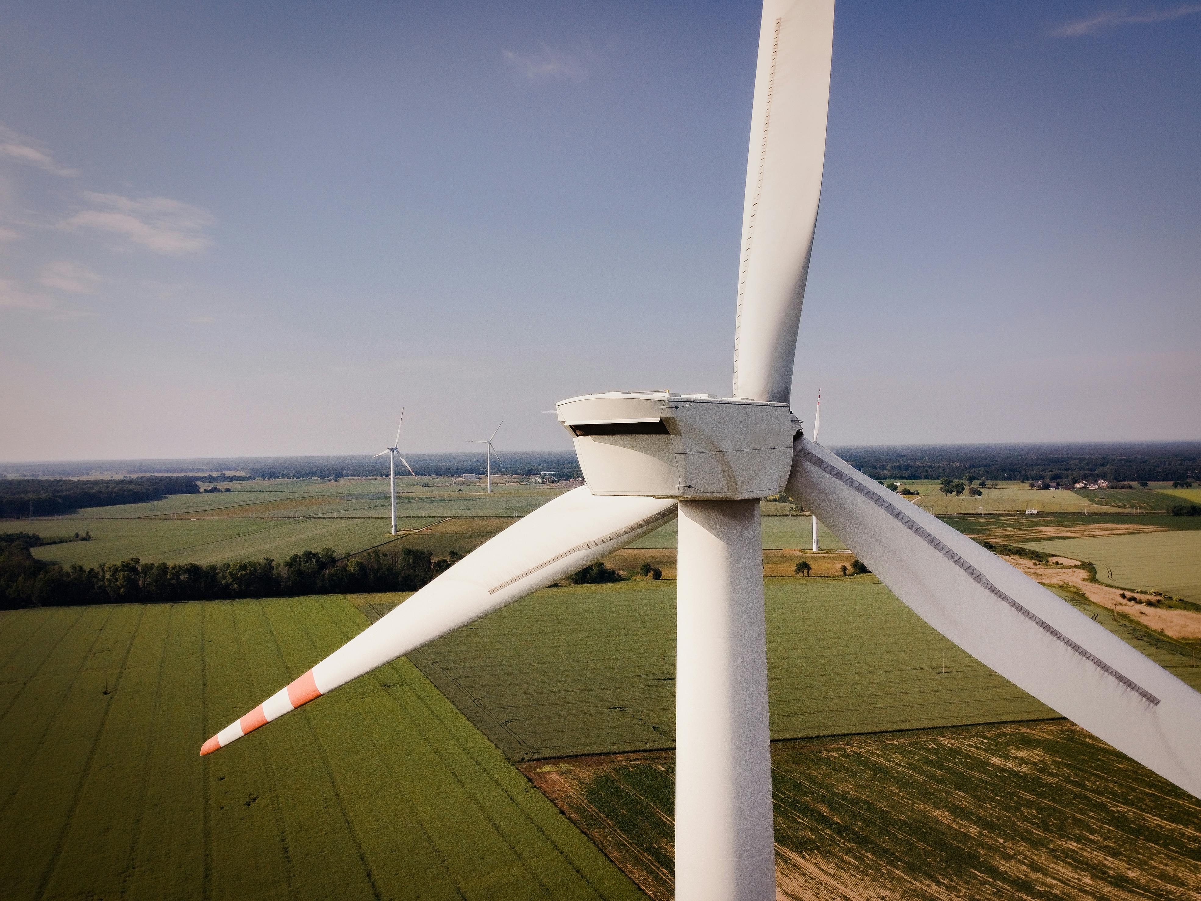 Auf einem Bild sind Windräder zu sehen und im Hintergrund grüne Landschaft. Bebildert wird damit ein Artikel zum NEKP (Nationaler Energie- und Klimaplan).