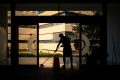 Die Silhouette eines Mannes beim Putzen des Eingangsbereiches eines öffentlichen Gebäudes: Der wertvollste Beruf für eine Gesellschaft ist die Reinigungskraft im Krankenhaus