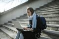 Berufliche Veränderung: Auch Erwachsene wollen noch den Beruf wechseln können. (Im Symbolbild: Eine junge Frau sitzt auf Stufen und schaut in einen Laptop.)