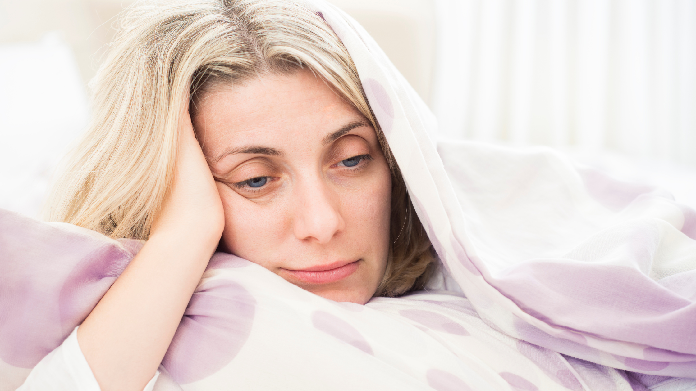 Der Kopf einer Frau schaut aus einer Decke hervor. Sie sieht müde aus.