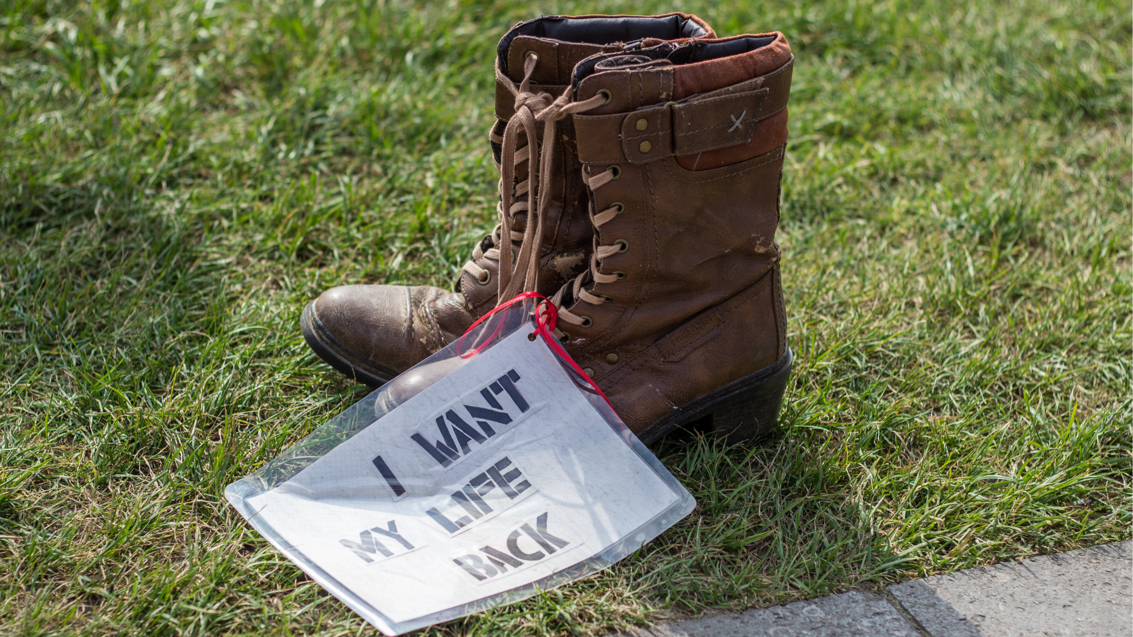 Schuhe mit Schild in der Wiese; Auf dem Schild steht: ich will mein Leben zurück