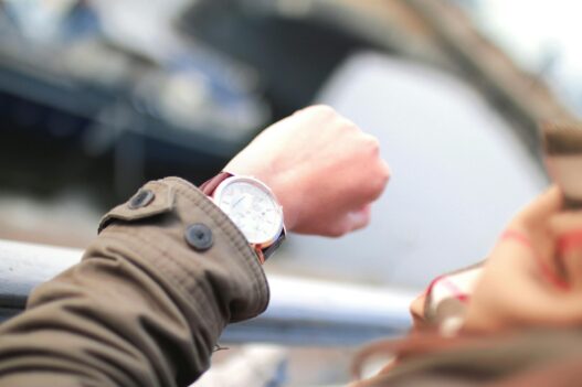 Countdown zur nächsten Immo-Pleite nach Signa (Symbolbild): Eine hält ihren Arm so, dass sie das Ziffernblatt ihrer Uhr lesen kann. Der Blick der Kamera ist über die Schulter der Person gerichtet, das Gesicht ist nicht zu sehen.