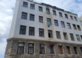 Foto zeigt Fassade des Hauses in der Flurschützstraße. Das Dach Ist abgetragen, Fenster fehlen.